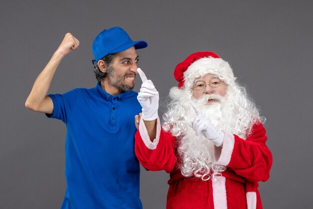 Front view of santa claus with male courier on grey wall