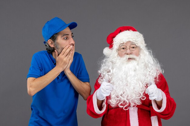 Front view of santa claus with male courier on grey wall