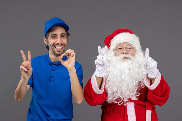 Front view of santa claus with male courier on the grey wall