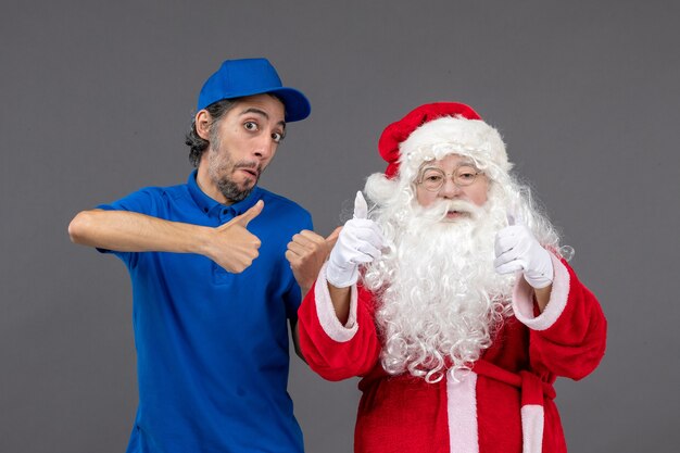 Front view of santa claus with male courier on the grey wall