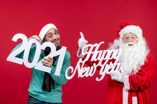 Front view santa claus with male holding and happy new year writing on red new year christmas holiday presents emotion