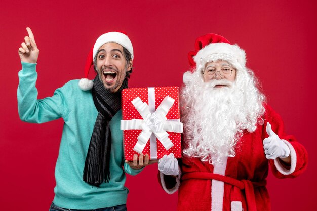 赤い贈り物の感情の赤いクリスマス新年に休日のプレゼントを保持している男性と正面のサンタクロース