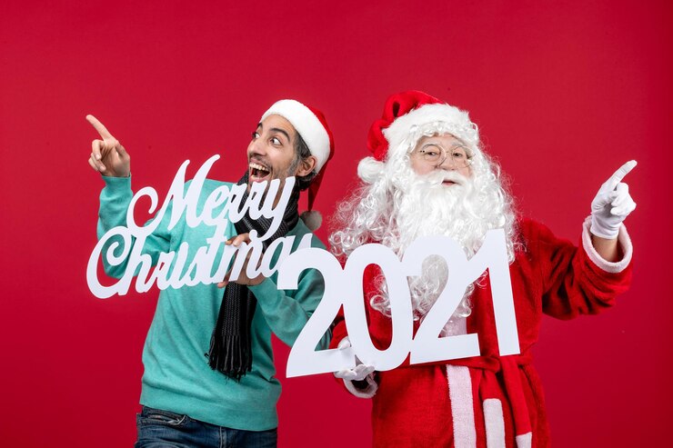 無料Photo 赤いクリスマスの色の休日に男性の保持とメリークリスマスの執筆と正面のサンタクロース