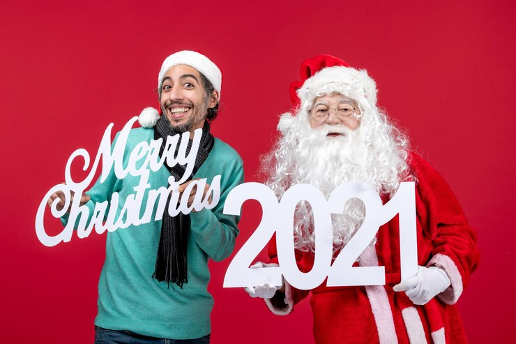無料Photo 男性の保持と赤いクリスマスプレゼントのメリークリスマスの書き込みと正面のサンタクロース