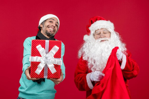 빨간색 책상 선물 크리스마스 감정 빨간색에 가방에서 선물을 꺼내는 남성과 전면 보기 산타 클로스