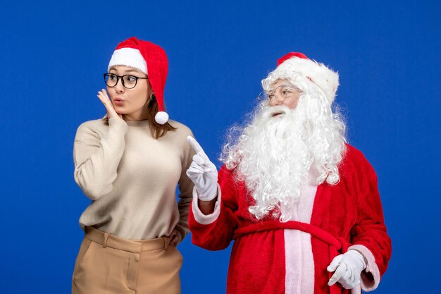 Front view santa claus with pretty female just standing on a blue color snow christmas emotion