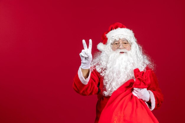 Vista frontale babbo natale con borsa rossa piena di regali sull'emozione natalizia delle vacanze di capodanno rosso