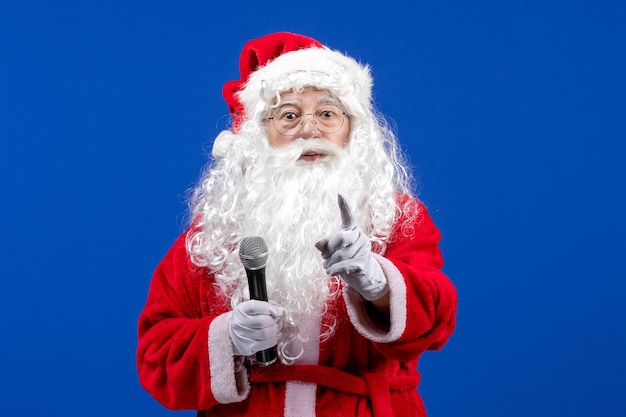 Front view santa claus with red suit and white beard holding mic on blue color new year xmas emotion