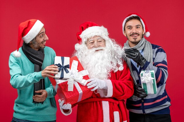 赤赤新年ギフト感情クリスマスにプレゼントを保持している2人の男性と正面のサンタクロース