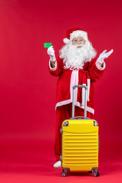 Front view of santa claus with yellow bag holding green bank card on the red wall