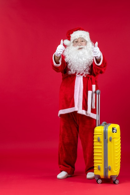 Front view of santa claus with yellow bag preparing for trip on red wall