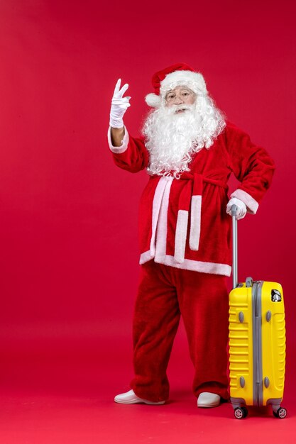 Front view of santa claus with yellow bag preparing for trip on red wall