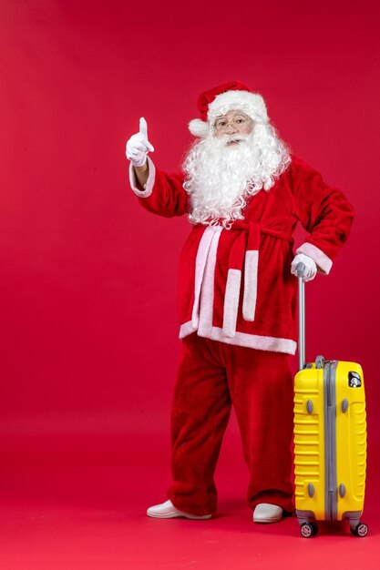 Front view of santa claus with yellow bag preparing for trip on red wall