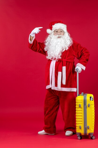 Front view of santa claus with yellow bag preparing for trip on red wall