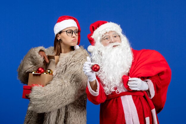 Front view santa claus with young female holding bag with presents and toys on blue holiday xmas color new year