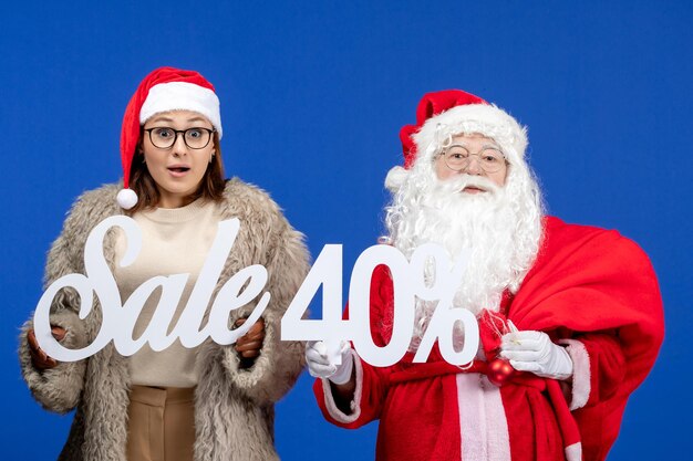 Front view santa claus with young female holding sale writings on blue holidays xmas