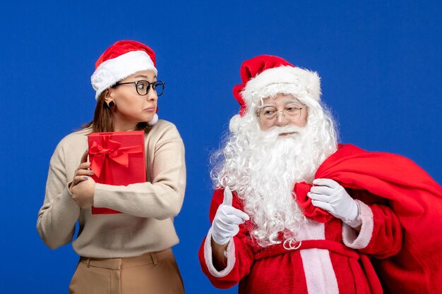 Front view santa claus with young female who is holding present on blue holidays emotion color