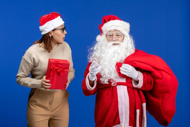 Front view santa claus with young female whos holding present on blue color holiday spirit emotions