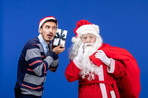 파란색 휴일 선물 크리스마스 색상에 선물로 가득 찬 젊은 남성 가방을 들고 전면 보기 산타 클로스