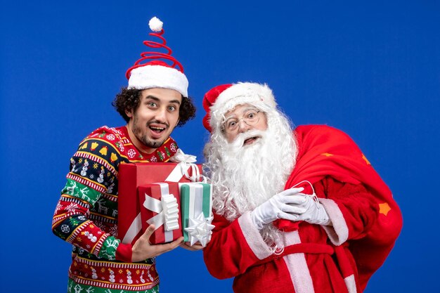 파란색 감정 크리스마스 휴일 색상에 젊은 남성과 다른 선물을 가진 전면 보기 산타 클로스