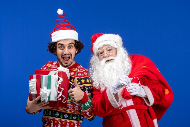 파란색 휴가 감정 크리스마스 색상에 젊은 남성과 다른 선물을 가진 전면 보기 산타 클로스