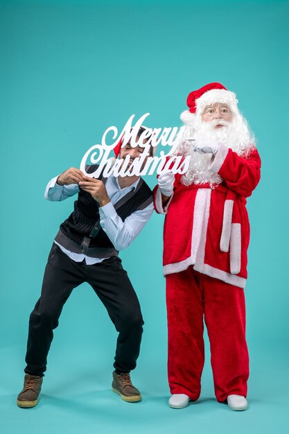 Front view santa claus with young male holding merry christmas writing on a blue background