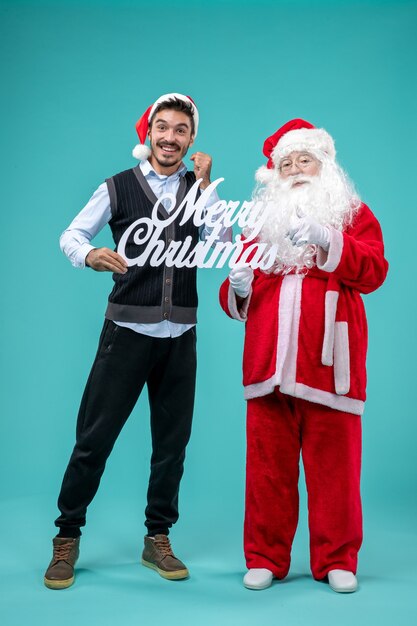 Front view santa claus with young male holding merry christmas writing on blue background