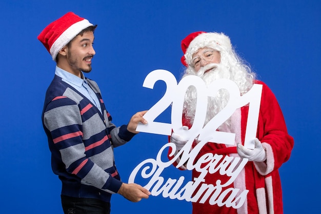 파란색 새 해 선물 크리스마스에 젊은 남성 들고와 메리 크리스마스 글과 전면보기 산타 클로스