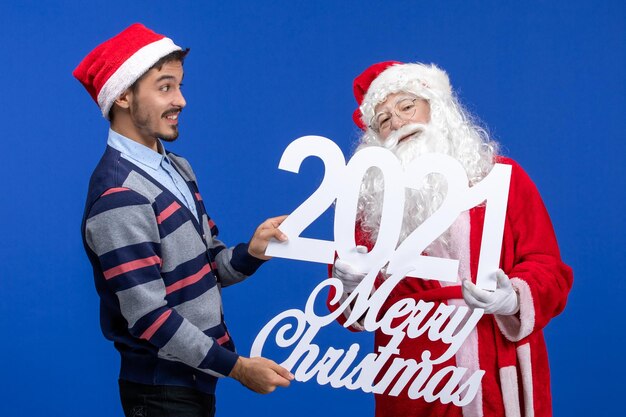 Front view santa claus with young male holding and merry christmas writings on blue new year present christmas