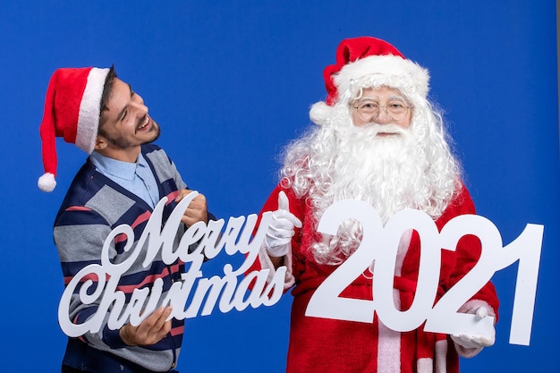 Front view santa claus with young male holding and merry christmas writings on blue