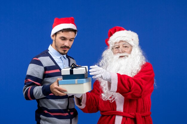 Front view santa claus with young male holding presents