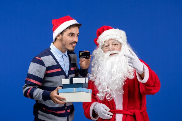 Front view santa claus with young male holding presents