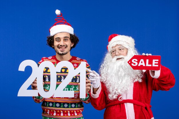 Front view santa claus with young male holding and sale writings on blue snow color new year xmas holidays