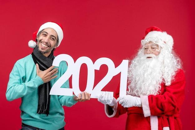 Front view santa claus with young male holding writing on red new year christmas holiday emotion presents