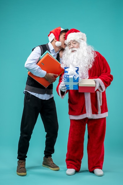 Foto gratuita vista frontale babbo natale con giovane maschio e regali su sfondo blu