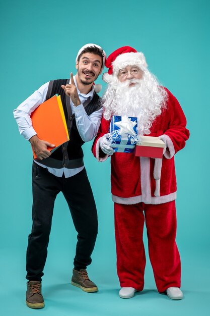 若い男性と正面図のサンタクロースと青い床にプレゼントクリスマス休暇雪年末年始