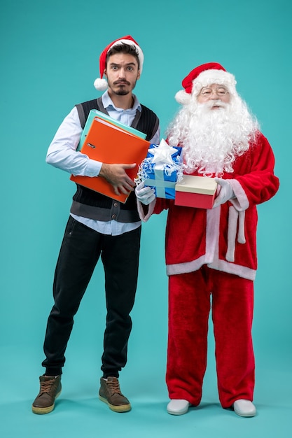 Front view of santa claus with young male and presents on blue wall