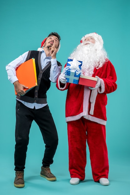 Front view of santa claus with young male and presents on blue wall