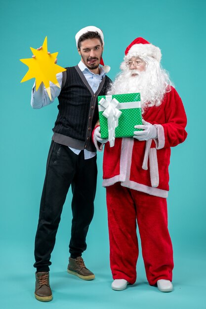 Vista frontale babbo natale con il giovane maschio che sta tenendo il cartello giallo su sfondo blu