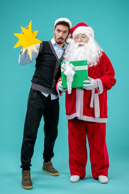 Front view santa claus with young male who's holding yellow sign on blue background