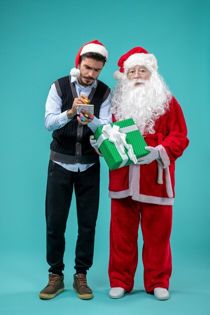 Front view santa claus with young male who's taking notes on the blue background