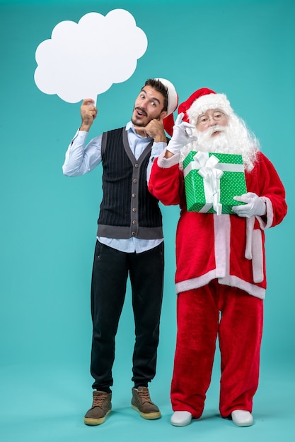 Foto gratuita babbo natale di vista frontale con i giovani maschii che tengono il segno bianco della nuvola sui precedenti blu