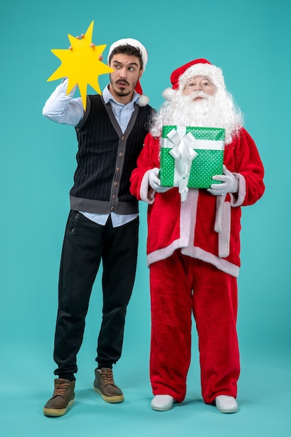 Front view santa claus with young male whos holding yellow sign on a blue background