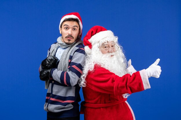 Front view of santa claus with young man on blue wall