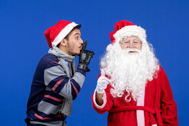 Front view of santa claus with young man on blue wall