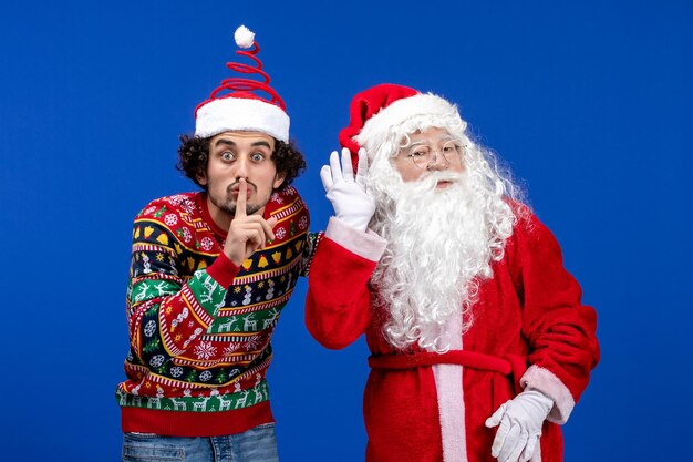 Front view of santa claus with young man on blue wall