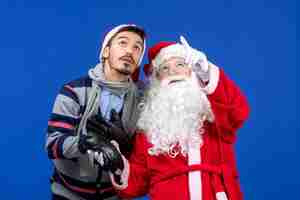 Free photo front view of santa claus with young man on the blue wall