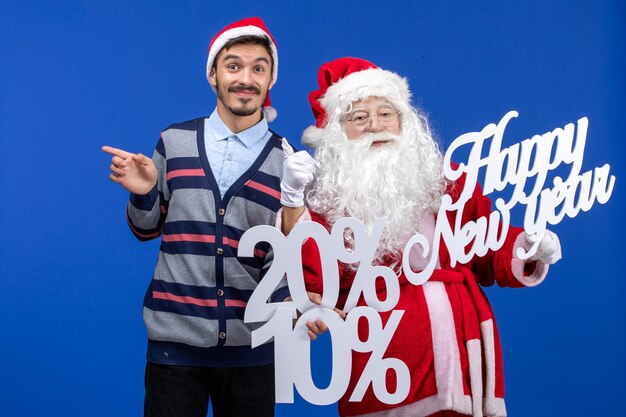 Front view of santa claus with young man holding Happy New Year and percent writings on a blue wall