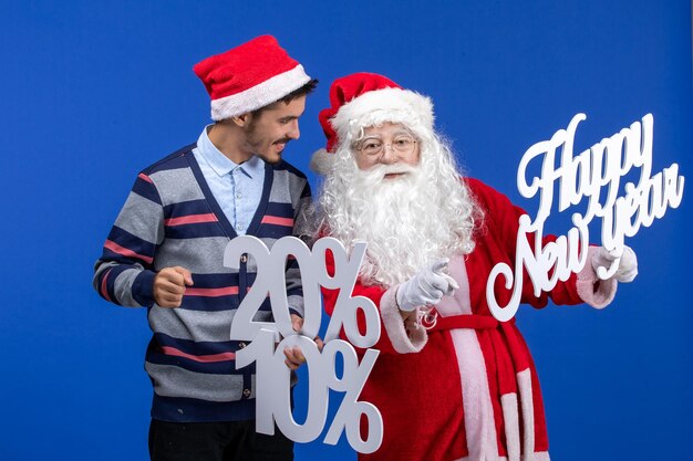 Front view of santa claus with young man holding happy New Year and percent writings on blue wall