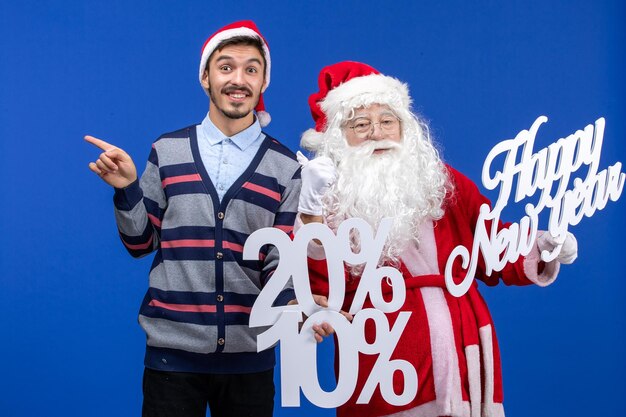 새해 복 많이 받으세요 및 파란 벽에 퍼센트 글을 들고 있는 젊은 남자와 산타 클로스의 전면 보기